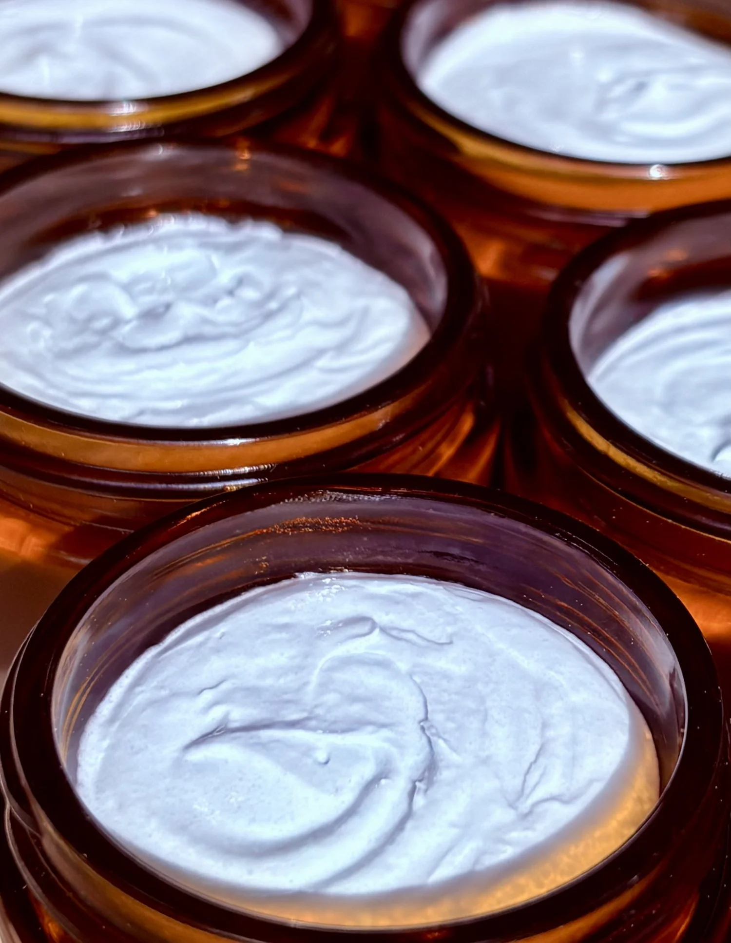 Open amber jars of whipped bison tallow cream